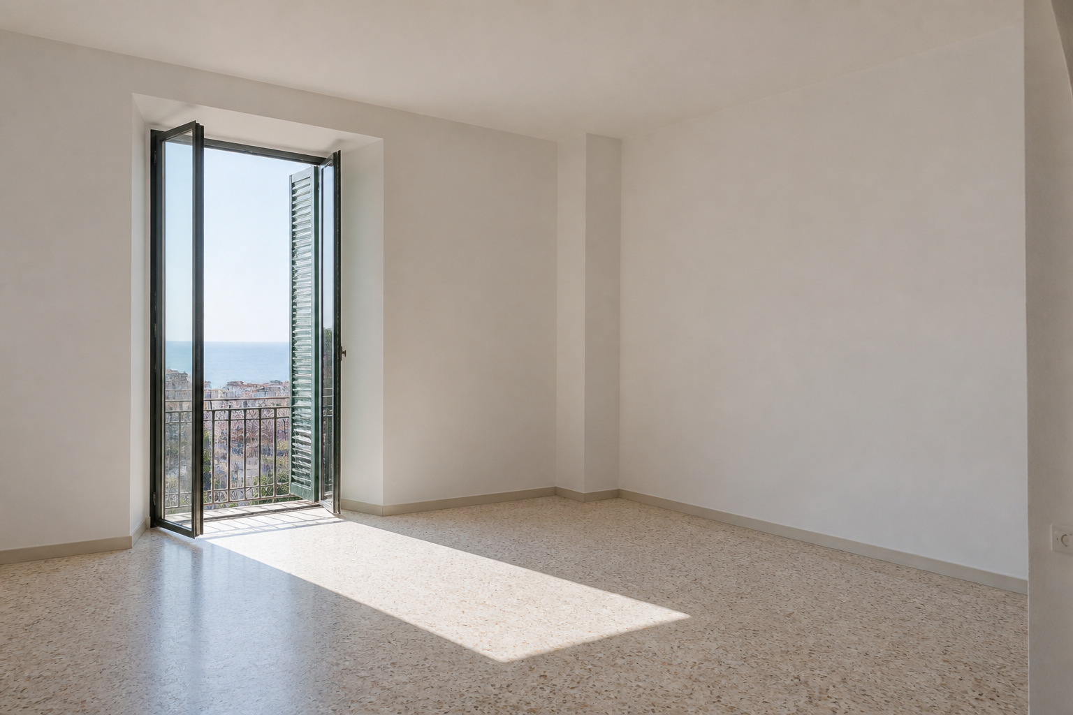 Empty apartment living room with a tall shuttered window onto the sea